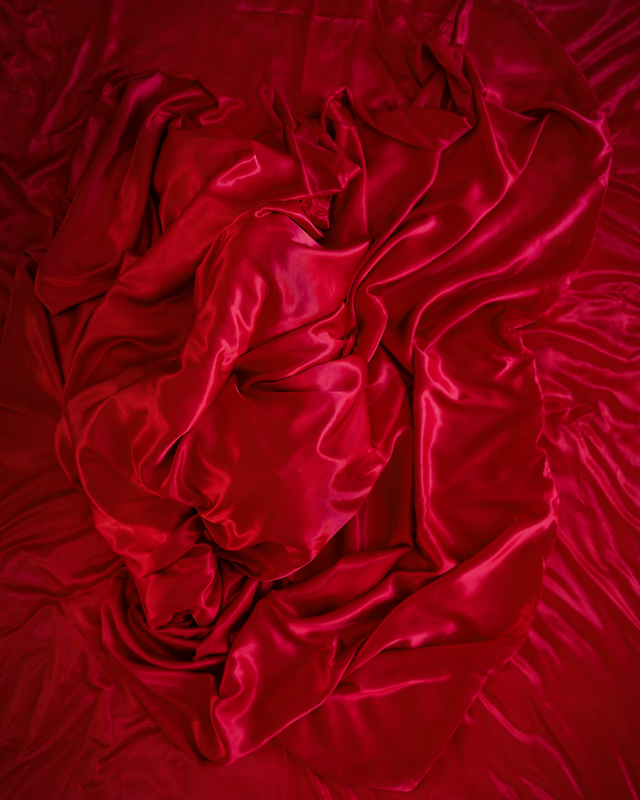 Person covered by a red sheet, embodying an emotion for installation