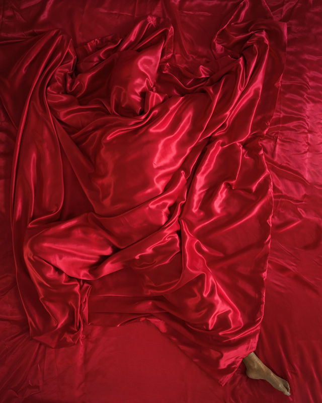 Person covered by a red sheet, embodying an emotion for installation