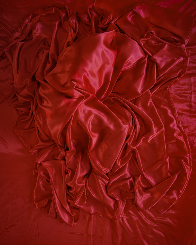 Person covered by a red sheet, embodying an emotion for installation