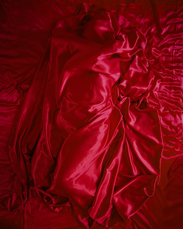 Person covered by a red sheet, embodying an emotion for installation