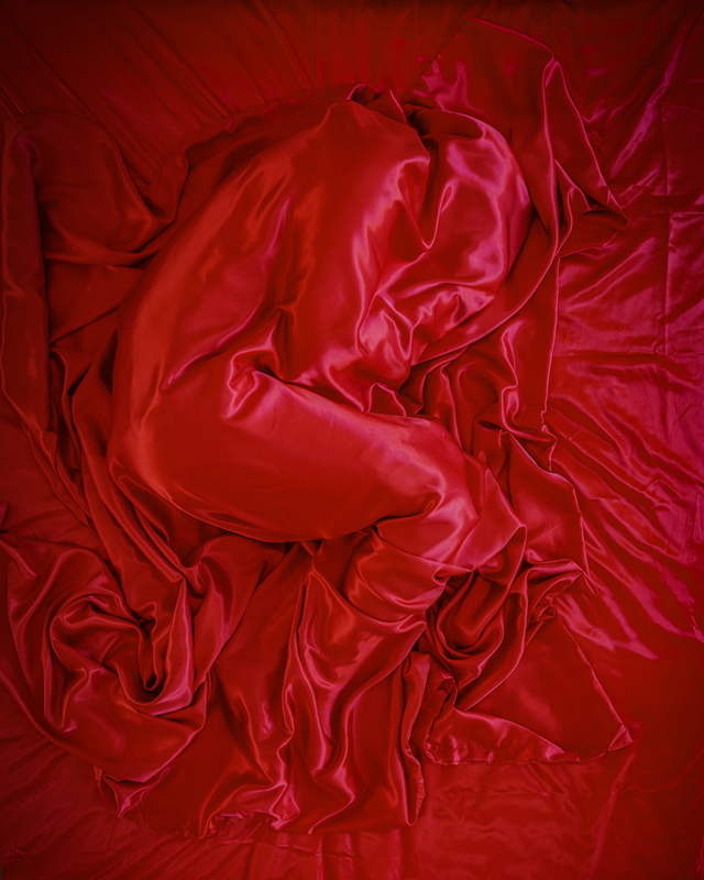 Person covered by a red sheet, embodying an emotion for installation