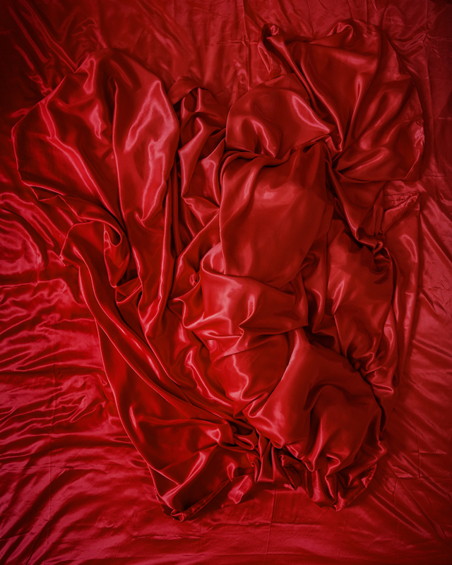 Person covered by a red sheet, embodying an emotion for installation
