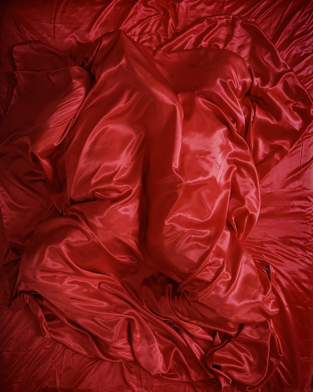 Person covered by a red sheet, embodying an emotion for installation